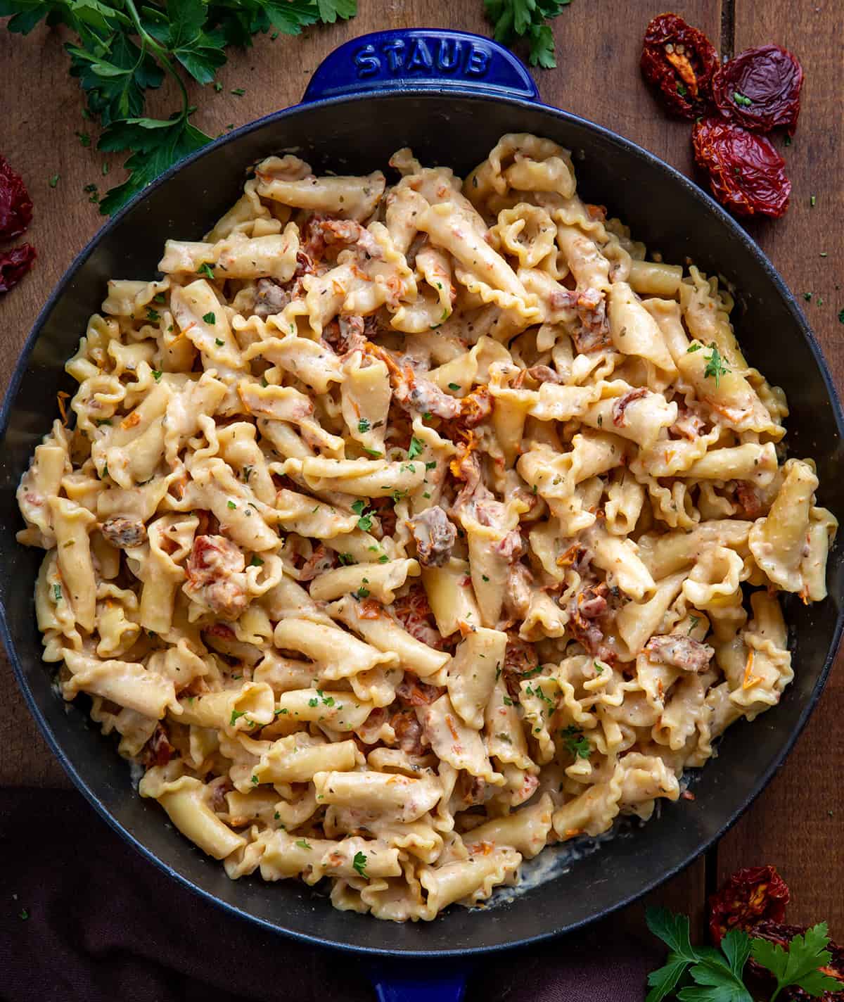Creamy Sun-Dried Tomato Pasta is a quick and flavorful pasta with sun-dried tomatoes, garlic, Parmesan, and Tuscan seasoning. Ready in under 30 minutes, this comforting dish is perfect for weeknight dinners. Skillet of Sun-Dried Tomato Pasta on a wooden table from overhead.