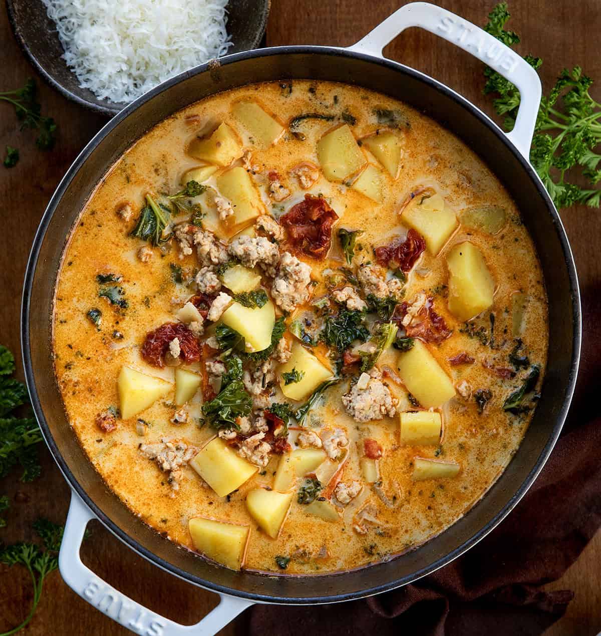 Warm, cozy, and packed with flavor, this Tuscan Chicken Potato Soup is a comforting one-pot meal you’ll want to make again and again! Pot of Tuscan Chicken Potato Soup on a wooden table from overhead.