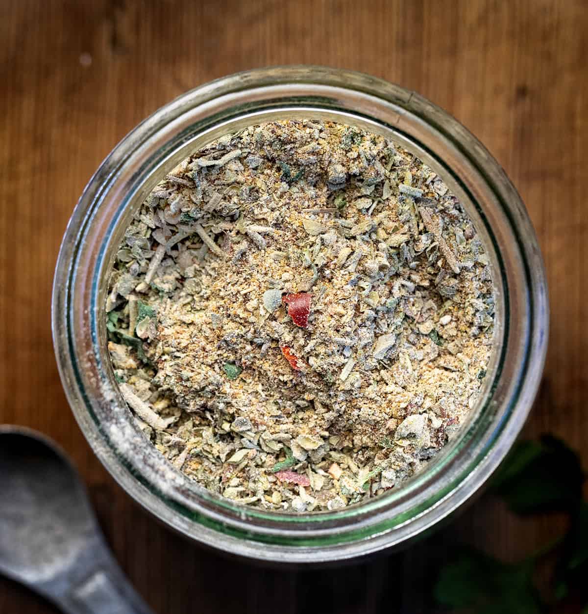 Homemade Tuscan Seasoning is a quick and easy spice blend that adds bold Italian flavor to your favorite meals. It’s made with dried herbs, garlic, and a touch of sun-dried tomato for a rich, savory taste! Looking down on a jar of Tuscan Seasoning on a wooden table.