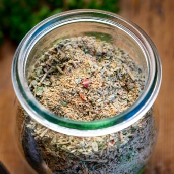 Jar of Tuscan Seasoning on a wooden table.