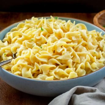 Blue bowl filled with Cafeteria Noodles on a wooden table.