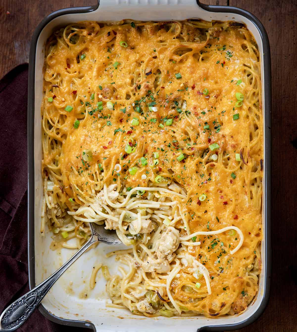 Pan of Cajun Chicken Spaghetti with a portion missing and a spoon in it from overhead.