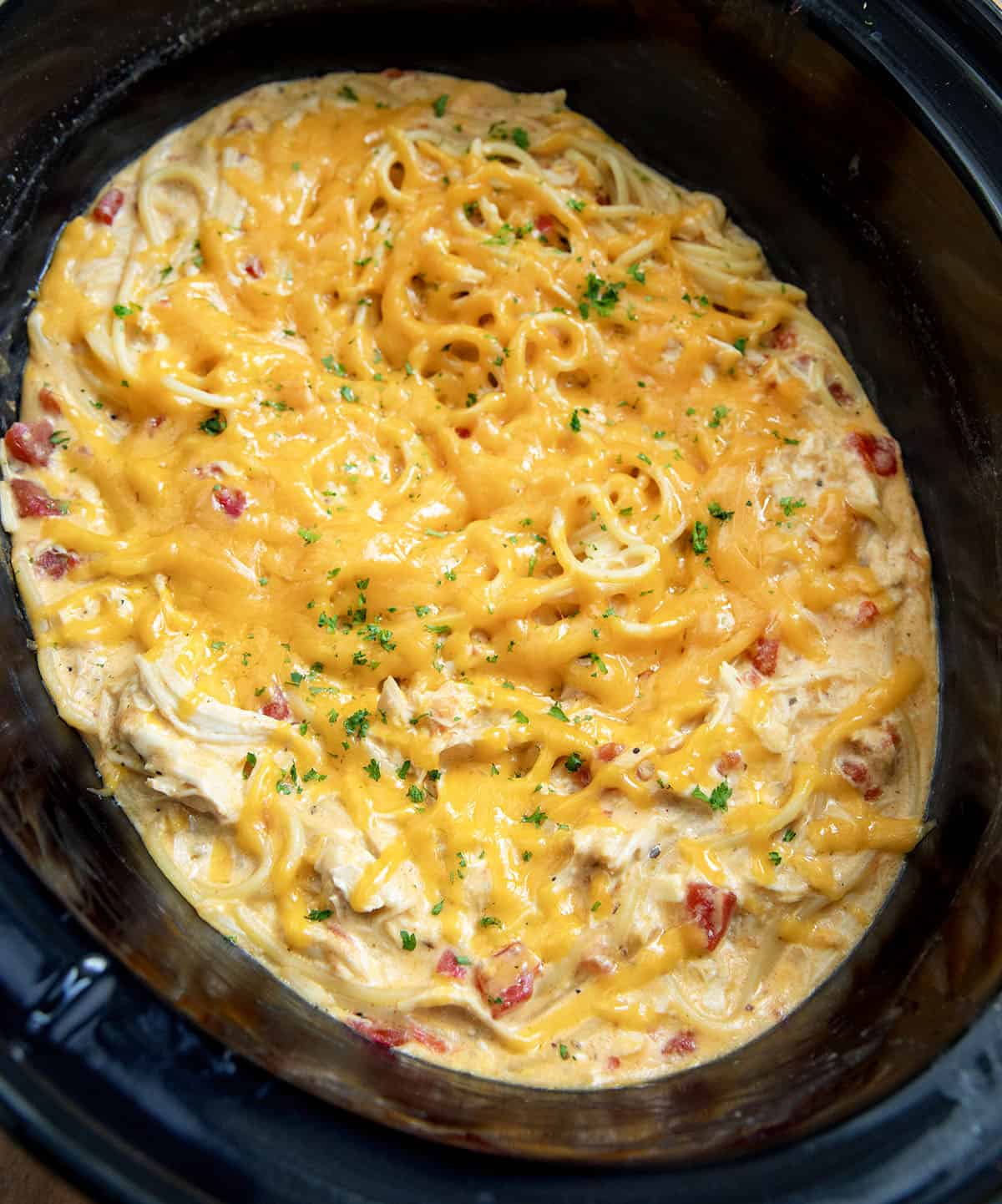 This Slow Cooker Cheesy Chicken Spaghetti is an easy, comforting dinner made with tender shredded chicken, a creamy cheese sauce, and perfectly cooked pasta! Close up of Cheesy Chicken Spaghetti in the slow cooker.