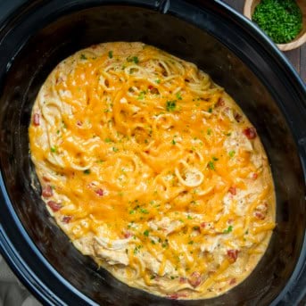 Slow Cooker Cheesy Chicken Spaghetti in the crockpot on a wooden table from overhead.