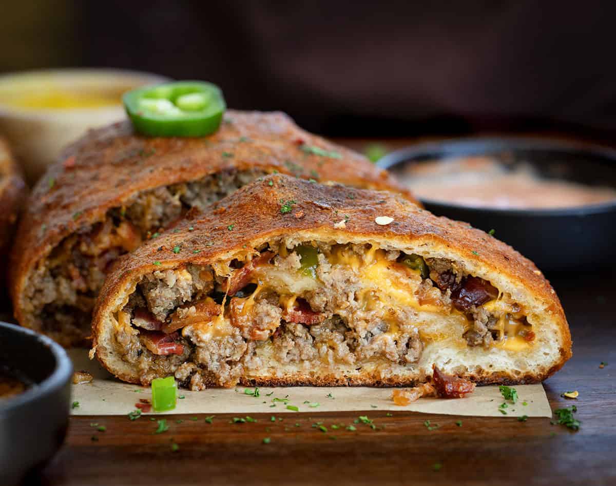 This Cowboy Garbage Bread is packed with seasoned ground beef, smoky bacon, sharp cheddar, and spicy jalapeños, all rolled up in golden pizza dough and brushed with flavorful Cowboy Butter! Looking straight on and close up at a slice of Cowboy Garbage Bread.