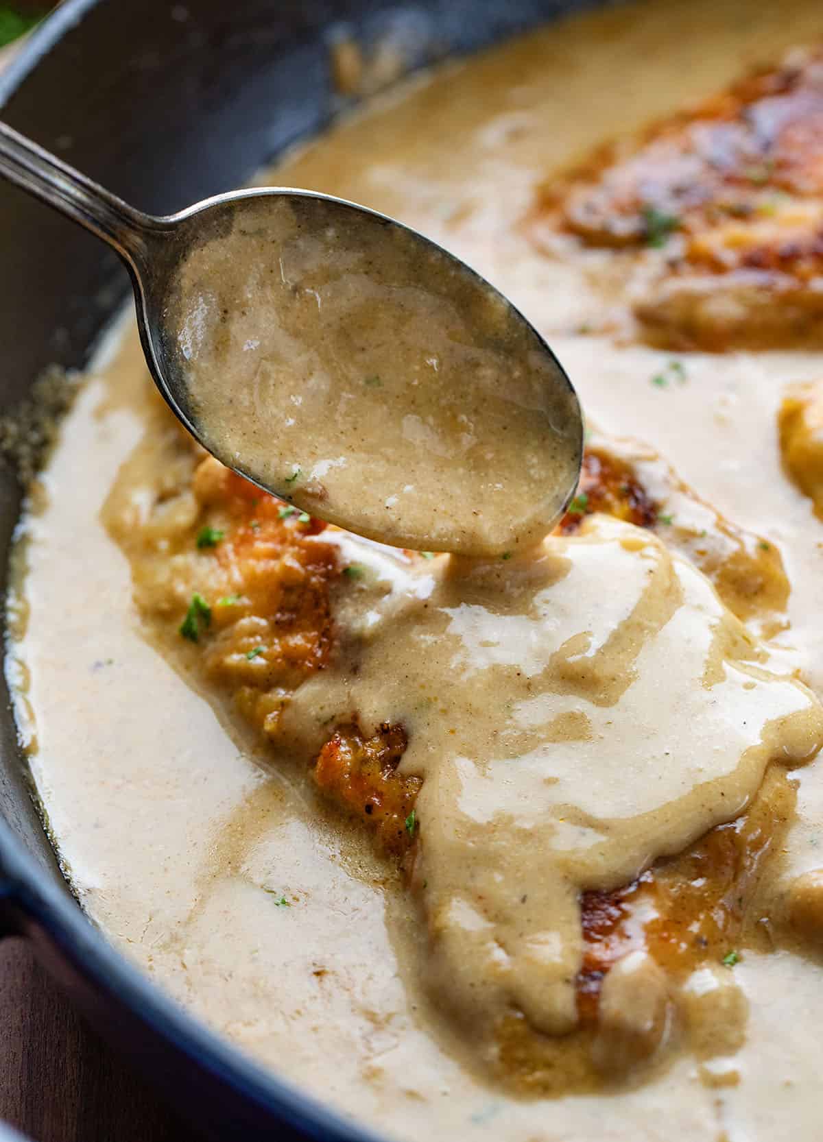 Easy Chicken and Gravy is a cozy, comforting dinner made with tender pan-seared chicken and a rich homemade onion gravy. Spooning gravy over chicken cutlets.