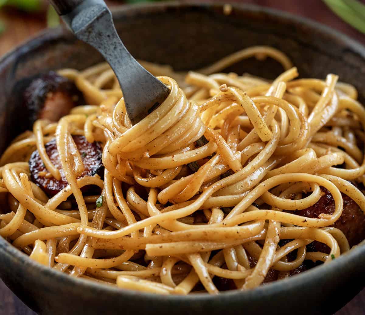 Creamy, garlicky linguine with smoky kielbasa and a touch of heat from sriracha. Quick, flavorful, and perfect for an easy weeknight dinner. Twirling linguine noodles around a fork.
