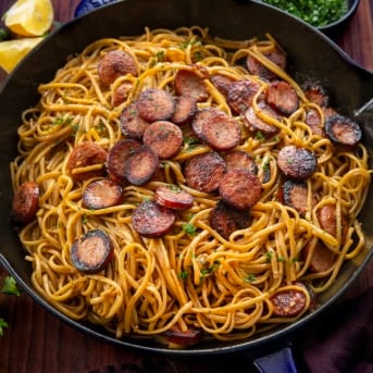 Skillet of Garlic Pasta with Kielbasa on a wooden table.