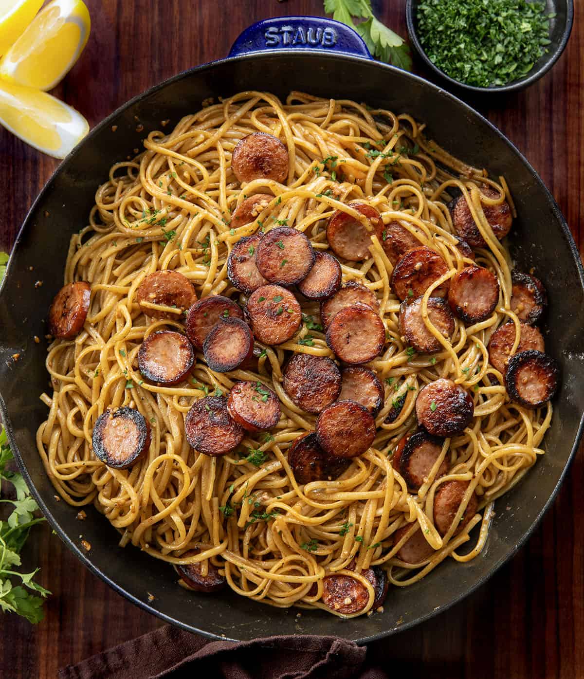 Creamy, garlicky linguine with smoky kielbasa and a touch of heat from sriracha. Quick, flavorful, and perfect for an easy weeknight dinner. Skillet of Garlic Pasta with Kielbasa on a wooden table from overhead.
