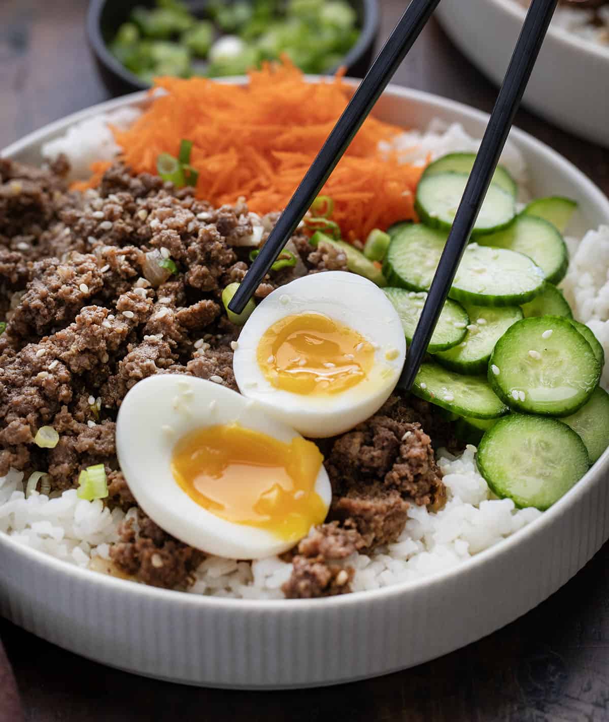Chop sticks picking up an egg from a Ground Beef Bulgogi Bowl.