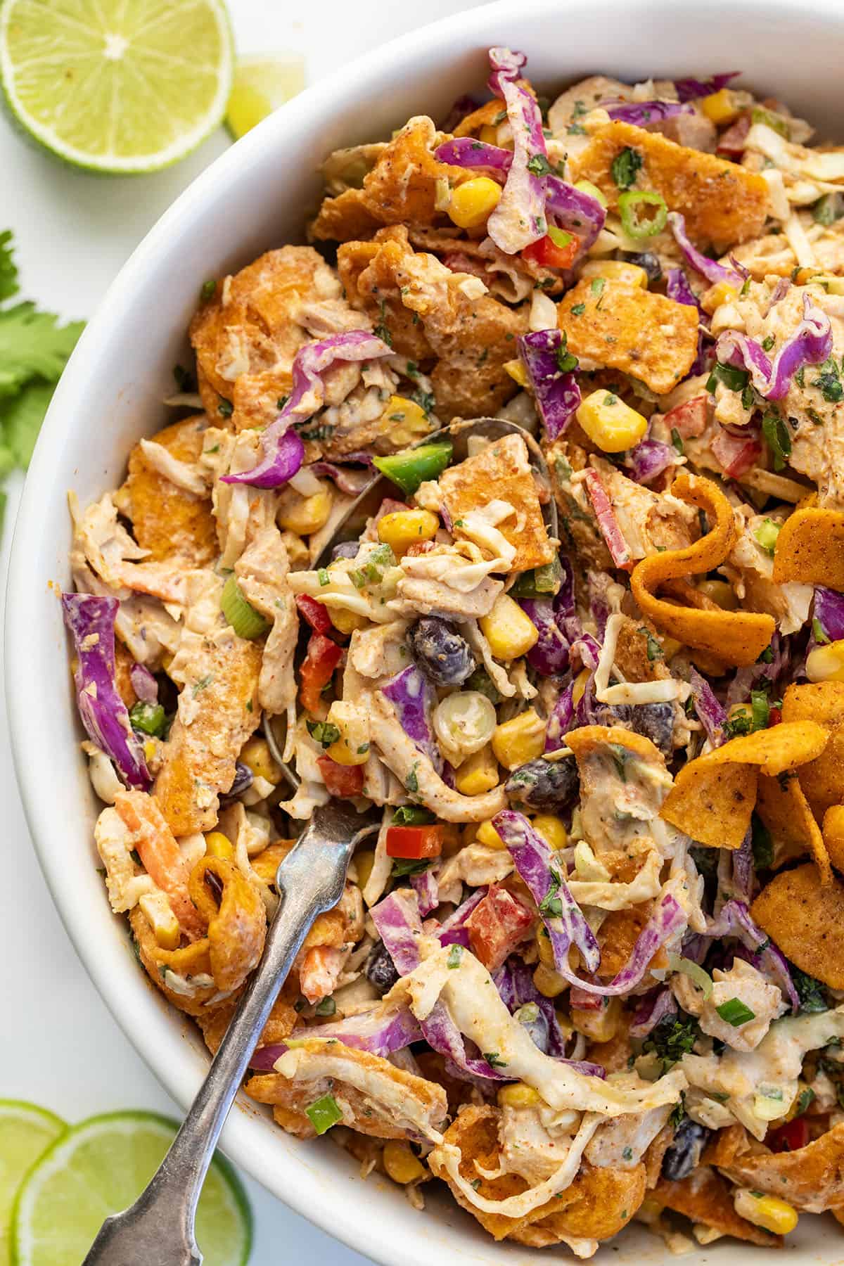 This Loaded Chicken Frito Cowboy Cabbage is a hearty, flavor-packed salad made with crunchy cabbage, shredded rotisserie chicken, black beans, corn, and fresh veggies, all tossed in a creamy chipotle dressing and finished with Chili Cheese Fritos! Close up of a spoon filled with Loaded Chicken Frito Cowboy Cabbage.