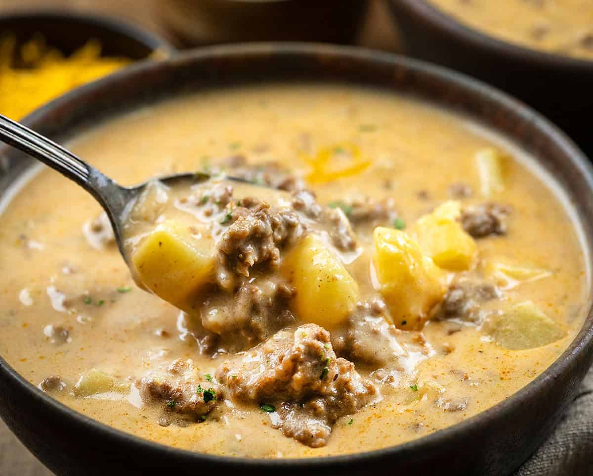 Ranch Cheesy Beef and Potato Soup is a rich and creamy soup made with ground beef, tender potatoes, cheddar cheese, and ranch seasoning! Spoonful of Ranch Cheesy Beef and Potato Soup held in the bowl.