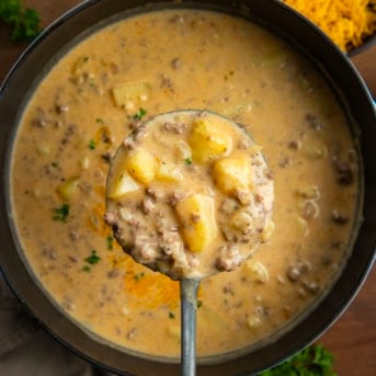 Ladle full of Ranch Cheesy Beef and Potato Soup being held above the pot from overhead.