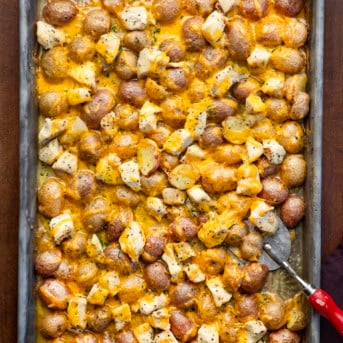 Sheetpan with Ranch Chicken and Potatoes on it and a spatula with a red handle.