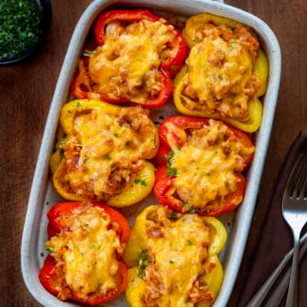 Seafood Stuffed Bell Peppers in a ceramic dish on a wooden table from overhead.
