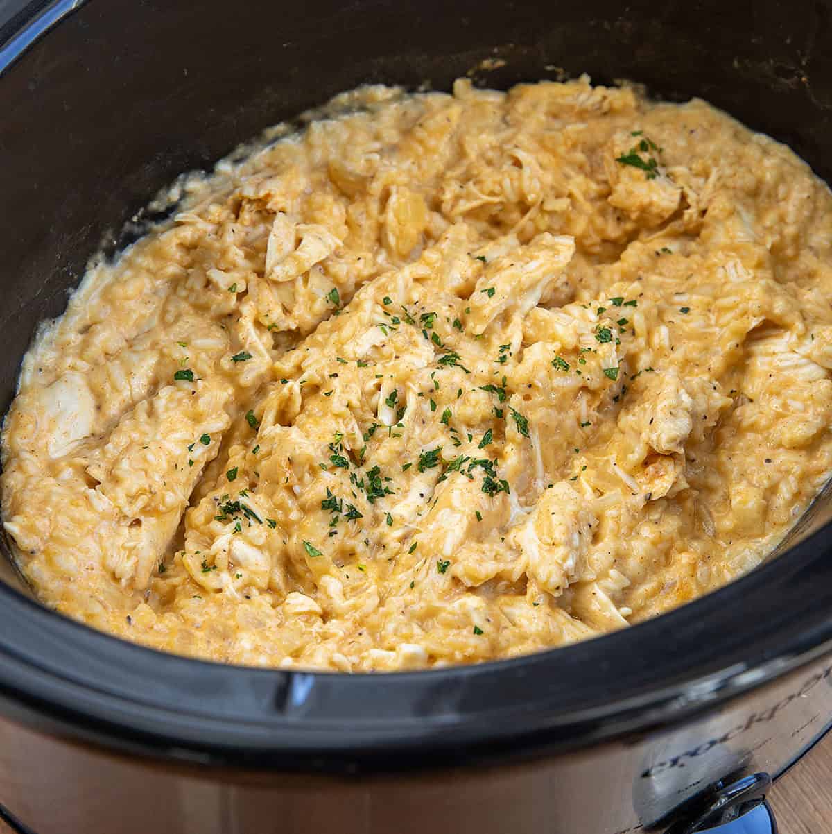 This Slow Cooker Chicken and Rice is a warm, comforting meal with tender chicken and creamy, flavorful rice cooked right in the crockpot! Crockpot filled with Chicken and Rice close up.