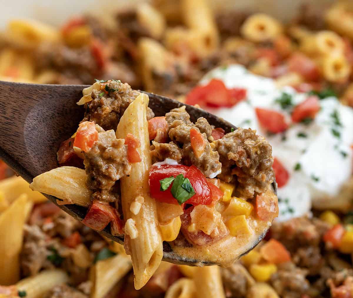 This Southwest Ground Beef Pasta is creamy, cheesy, and full of bold Southwest flavors. Easy to make, flexible with ingredients, and perfect for meal prep! Wooden spoon with Southwest Ground Beef Pasta on it, very close up.