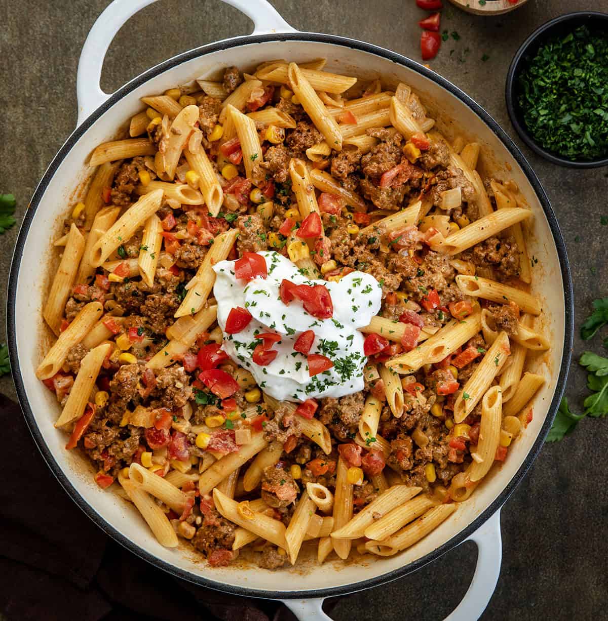 This Southwest Ground Beef Pasta is creamy, cheesy, and full of bold Southwest flavors. Easy to make, flexible with ingredients, and perfect for meal prep! White skillet of Southwest Ground Beef Pasta on a table from overhead.
