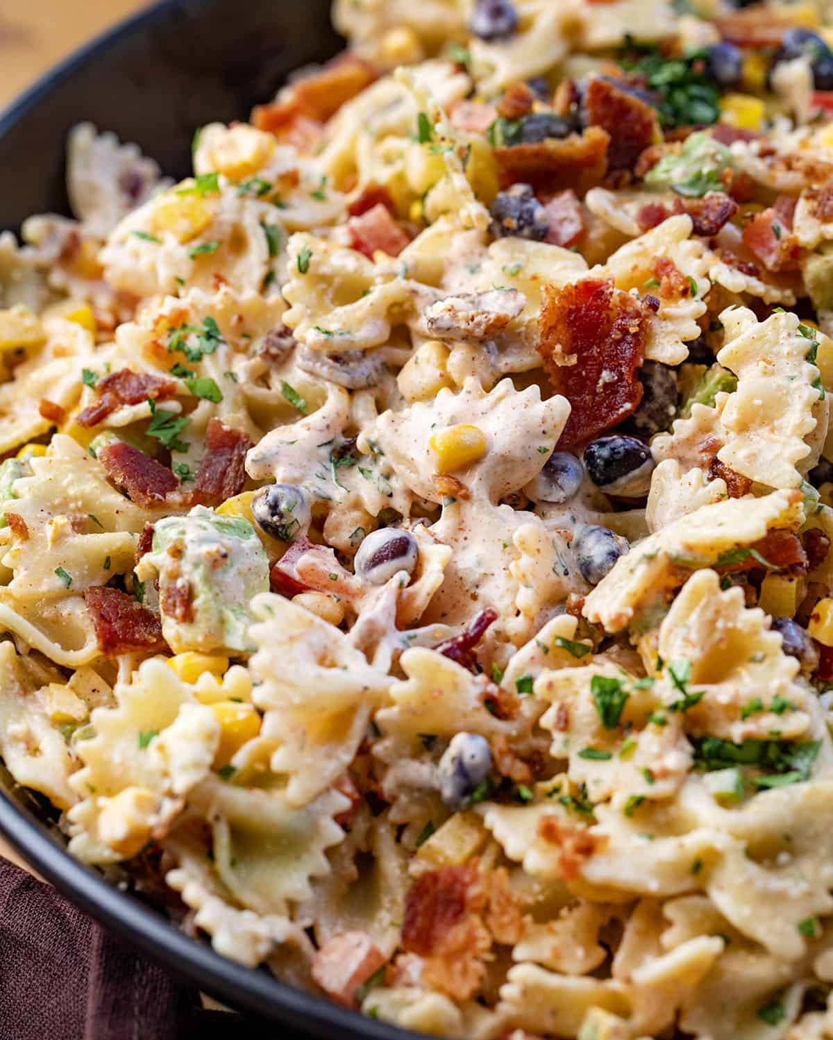 This Southwest Pasta Salad is bold, creamy, and packed with flavor in every bite. Made with bowtie pasta, black beans, corn, bacon, fresh veggies, and a chili-lime dressing, it’s an easy make-ahead dish that’s fresh, hearty, and full of Southwest flavor! Close up of Southwest Pasta Salad.