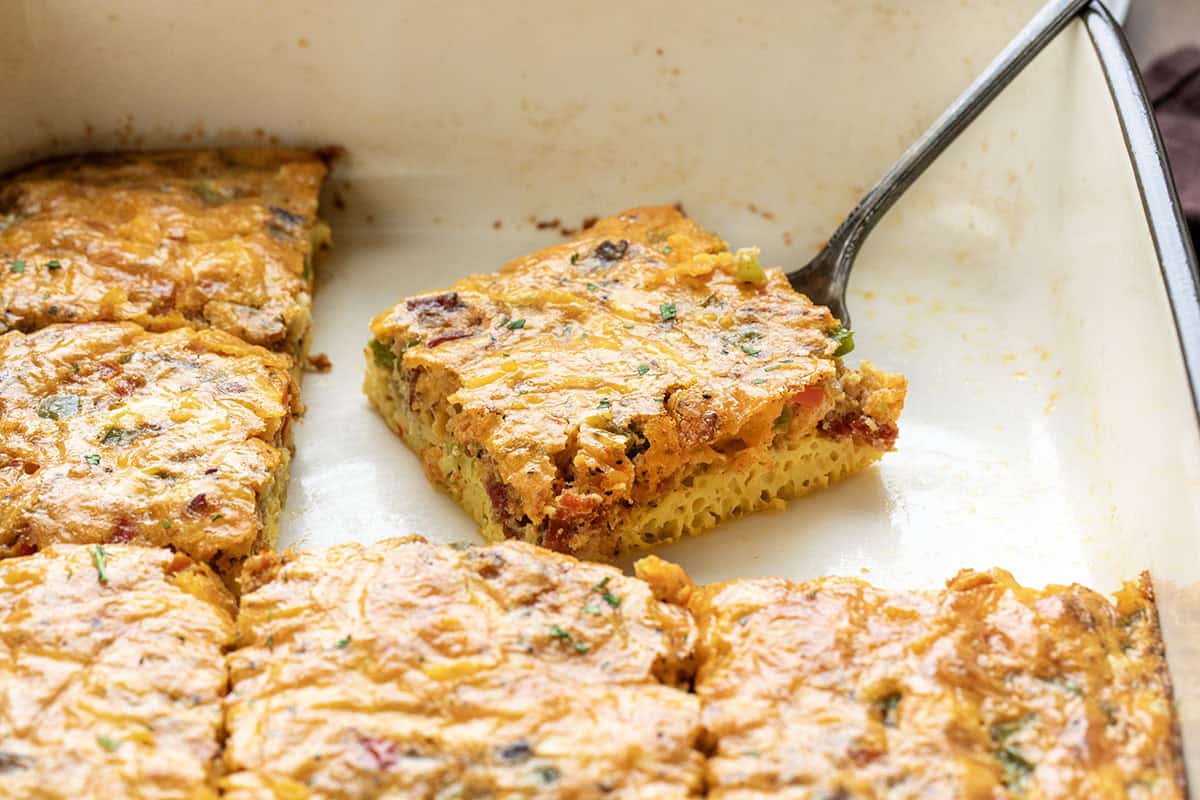 This Western Omelette Breakfast Bake is a quick, family-friendly breakfast that combines fluffy eggs, smoky bacon, sautéed peppers and onions, and melty cheddar cheese, all baked in one dish! Piece of Western Omelette Breakfast Bake in the pan.