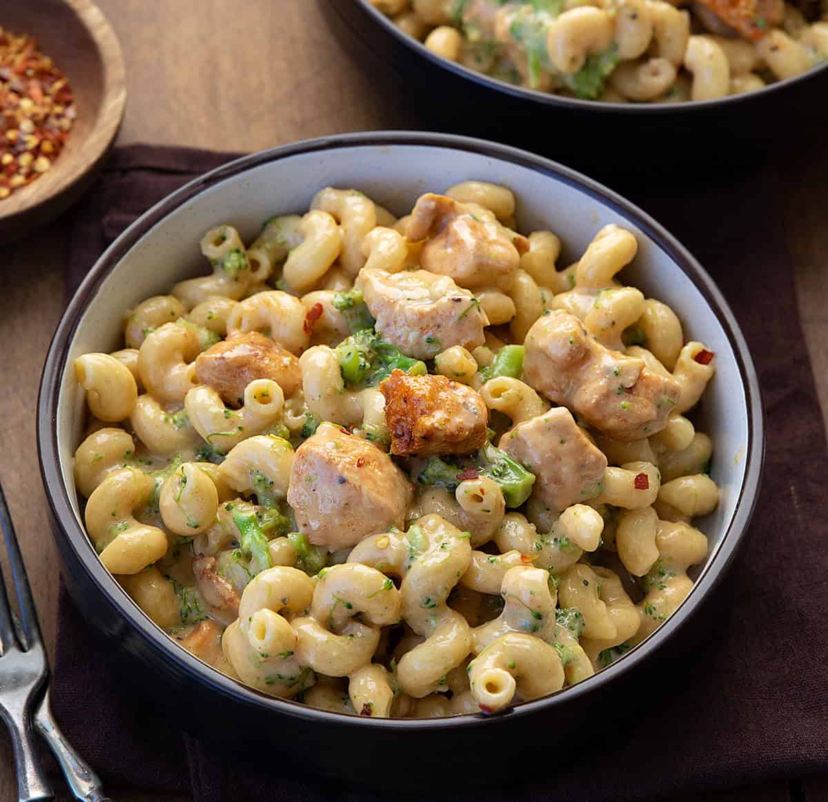 This White Cheddar Chicken Pasta with Broccoli is a creamy, comforting dinner made with tender chicken, cavatappi pasta, and crisp-tender broccoli all coated in a smooth white cheddar cheese sauce! Close up of a bowl of White Cheddar Chicken Pasta with Broccoli.