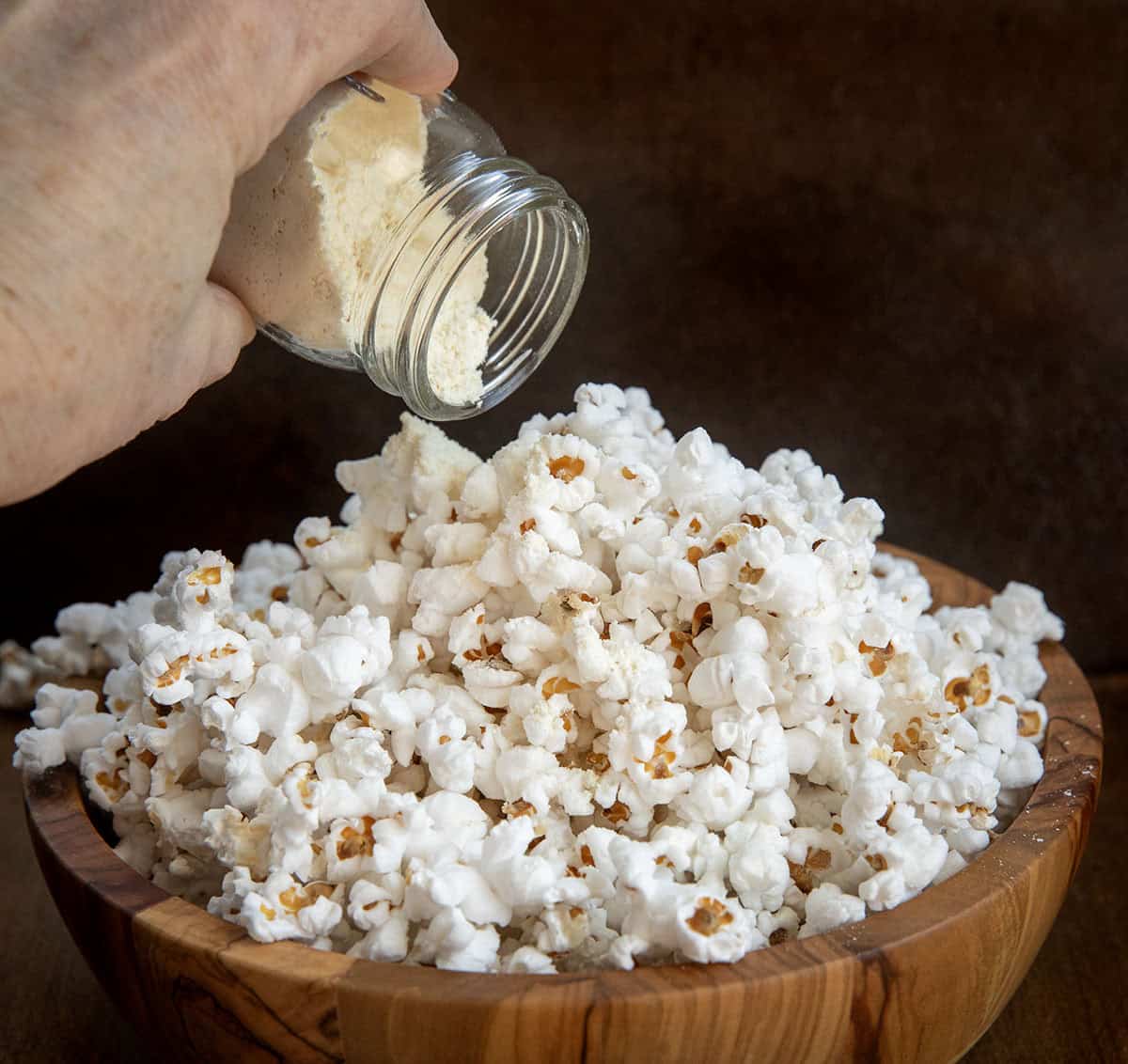 A quick and easy way to make your popcorn cheesy, flavorful, and irresistible. Just mix the spices and cheddar powder, shake on your favorite snack, and enjoy a homemade savory treat that’s ready in minutes! Adding White Cheddar Popcorn Seasoning to popcorn.