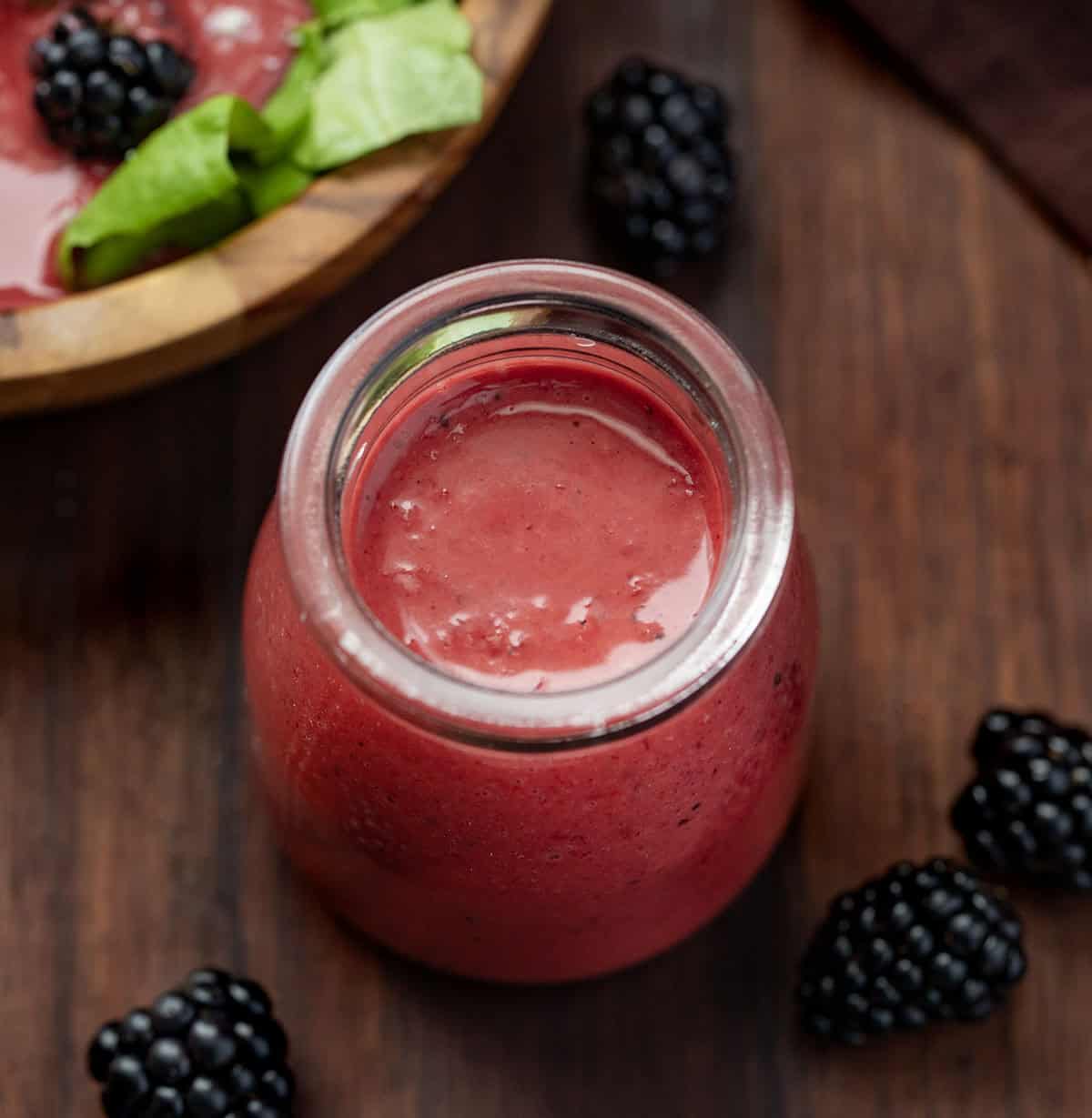 Looking down on a bottle of Blackberry Vinaigrette on a wooden table.
