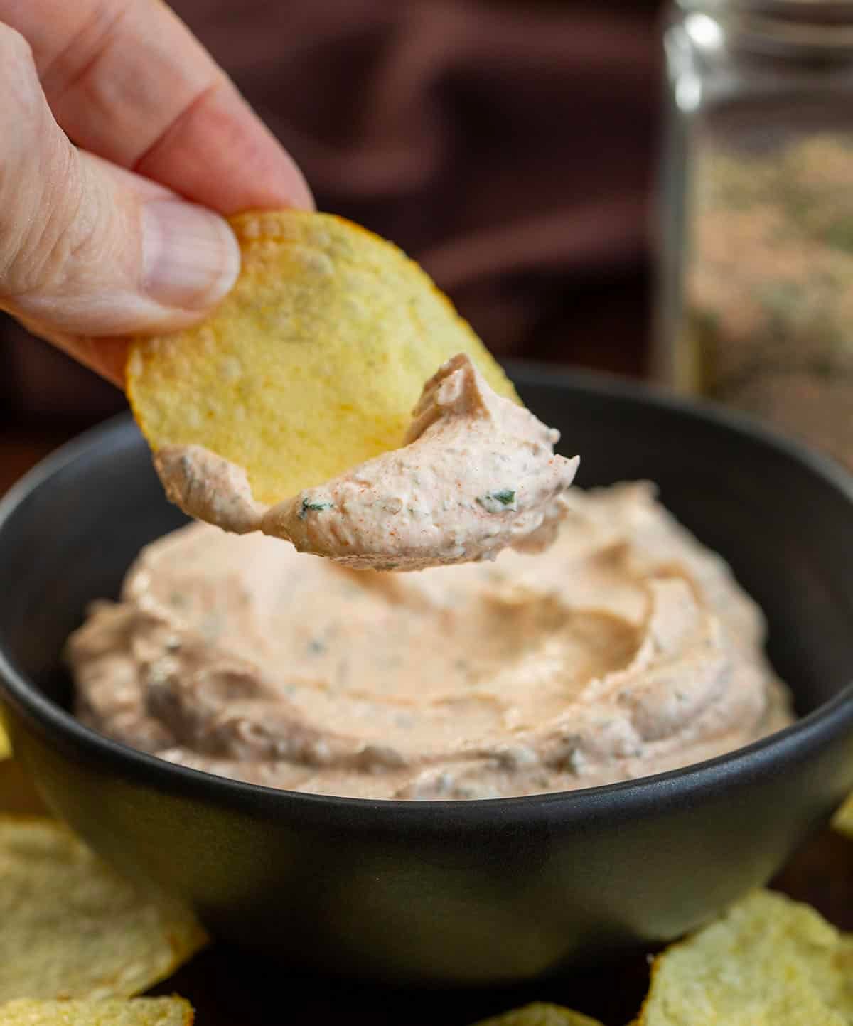 This blackened ranch seasoning is a quick homemade mix that turns into an easy dip or creamy dressing in just a few minutes. It starts with simple pantry spices and adds a little ranch-style herb flavor with a hint of spice and smoky depth. Blackened Ranch Seasoning mixed with sour cream to make a dip with a hand holding a chip covered in the dip.