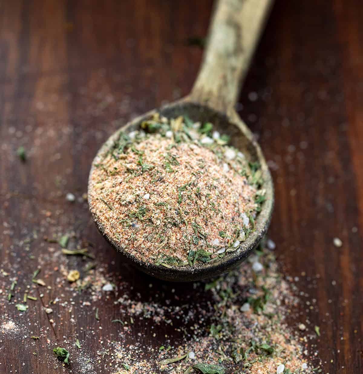 This blackened ranch seasoning is a quick homemade mix that turns into an easy dip or creamy dressing in just a few minutes. It starts with simple pantry spices and adds a little ranch-style herb flavor with a hint of spice and smoky depth. Wooden measuring spoon with Blackened Ranch Seasoning in it and some spilling on the wooden table.