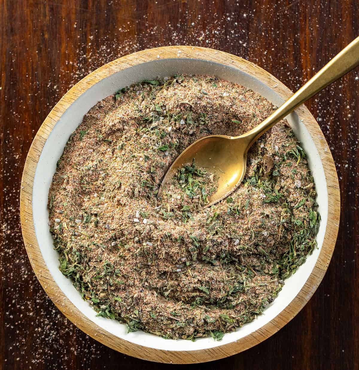 This blackened ranch seasoning is a quick homemade mix that turns into an easy dip or creamy dressing in just a few minutes. It starts with simple pantry spices and adds a little ranch-style herb flavor with a hint of spice and smoky depth. Bowl of Blackened Ranch Seasoning with a small golden spoon in the bowl on a wooden table from overhead.
