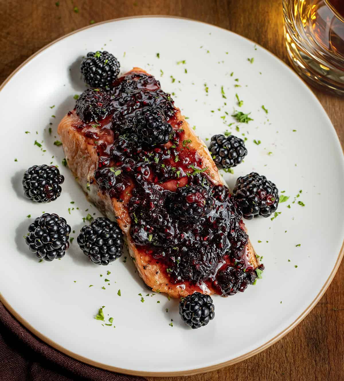 This bourbon blackberry salmon is a sweet and savory dinner made with tender baked salmon and a rich blackberry bourbon sauce. It’s bold, flavorful, and surprisingly easy to make for a restaurant-quality meal at home. One plate of Bourbon Blackberry Salmon on a wooden table with a glass of bourbon.