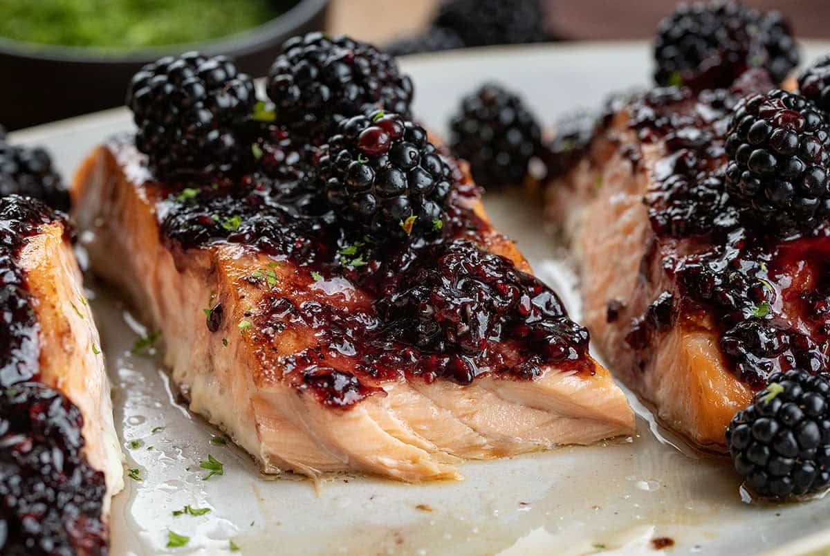 This bourbon blackberry salmon is a sweet and savory dinner made with tender baked salmon and a rich blackberry bourbon sauce. It’s bold, flavorful, and surprisingly easy to make for a restaurant-quality meal at home. Piece of Bourbon Blackberry Salmon with a bite removed showing inside flakey texture.