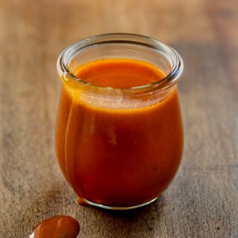 Jar of Buffalo Sauce on a wooden table close up.