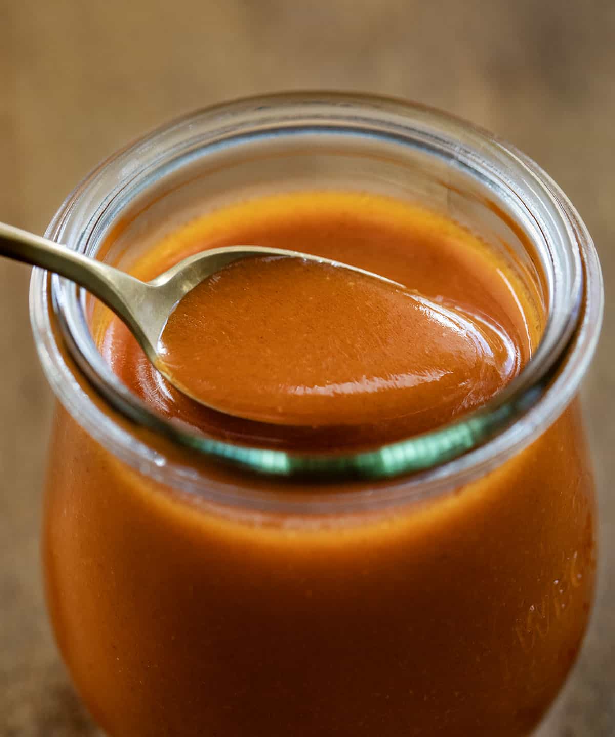 This Buffalo Sauce is rich, buttery, and packed with bold, tangy heat. It comes together in just minutes on the stovetop for a smooth, glossy sauce that clings perfectly to wings, chicken, and more. It’s quick, easy, and so much better than anything store-bought! Spoonful of Buffalo Sauce being held in the jar.