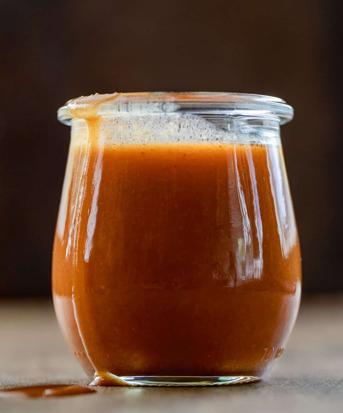 This Buffalo Sauce is rich, buttery, and packed with bold, tangy heat. It comes together in just minutes on the stovetop for a smooth, glossy sauce that clings perfectly to wings, chicken, and more. It’s quick, easy, and so much better than anything store-bought! Jar of Buffalo Sauce on a wooden table close up.