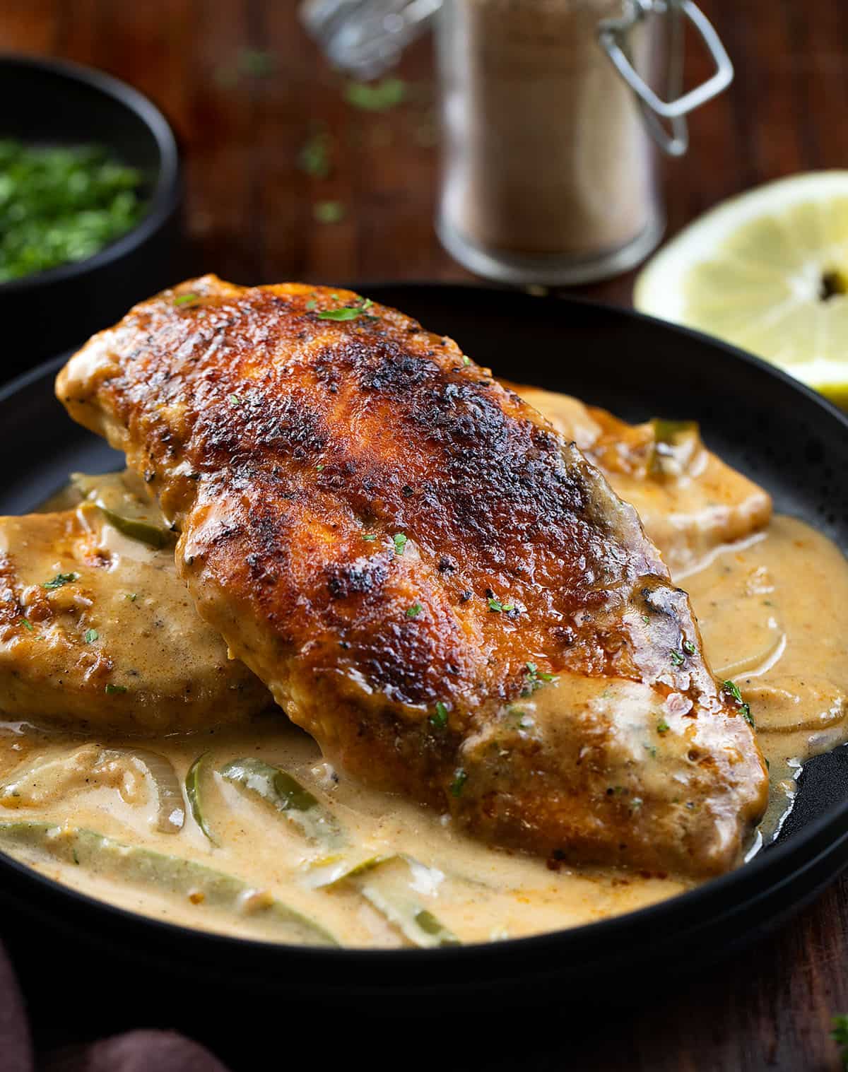 This Cajun Chicken and Gravy is an easy skillet dinner made with tender pan-seared chicken and a creamy onion and pepper gravy. Cajun Chicken and Gravy on a black plate stacked and showing the flavorful chicken.
