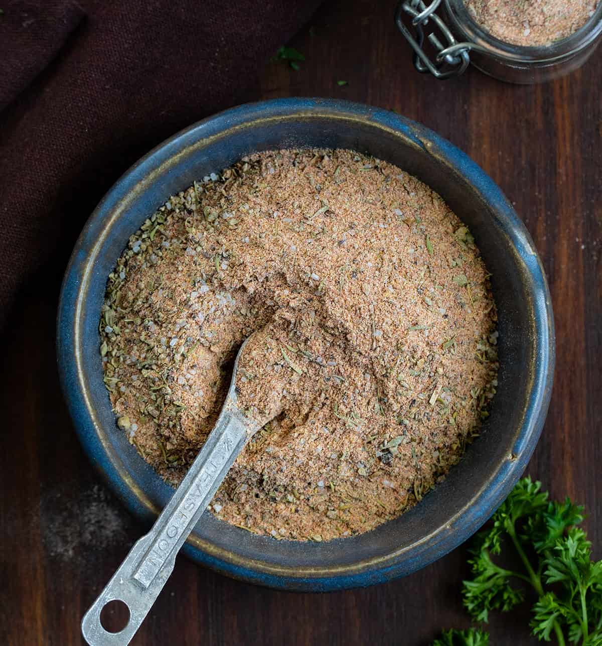 This homemade Cajun seasoning is the kind of simple pantry staple that makes everyday cooking a little more exciting. It comes together in just a few minutes and gives you that classic Cajun flavor you can sprinkle on just about anything. Blue bowl of Cajun Seasoning with a measuring spoon in it on a wooden table.