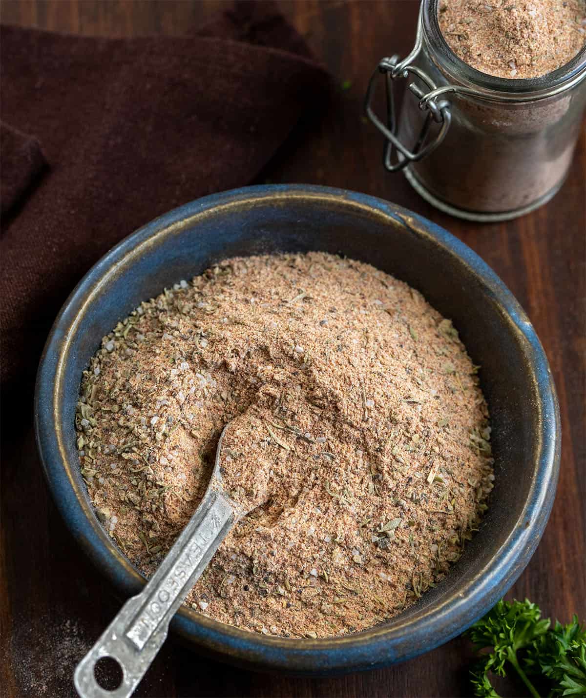 This homemade Cajun seasoning is the kind of simple pantry staple that makes everyday cooking a little more exciting. It comes together in just a few minutes and gives you that classic Cajun flavor you can sprinkle on just about anything. Blue bowl of Cajun Seasoning with a measuring spoon in it on a wooden table.