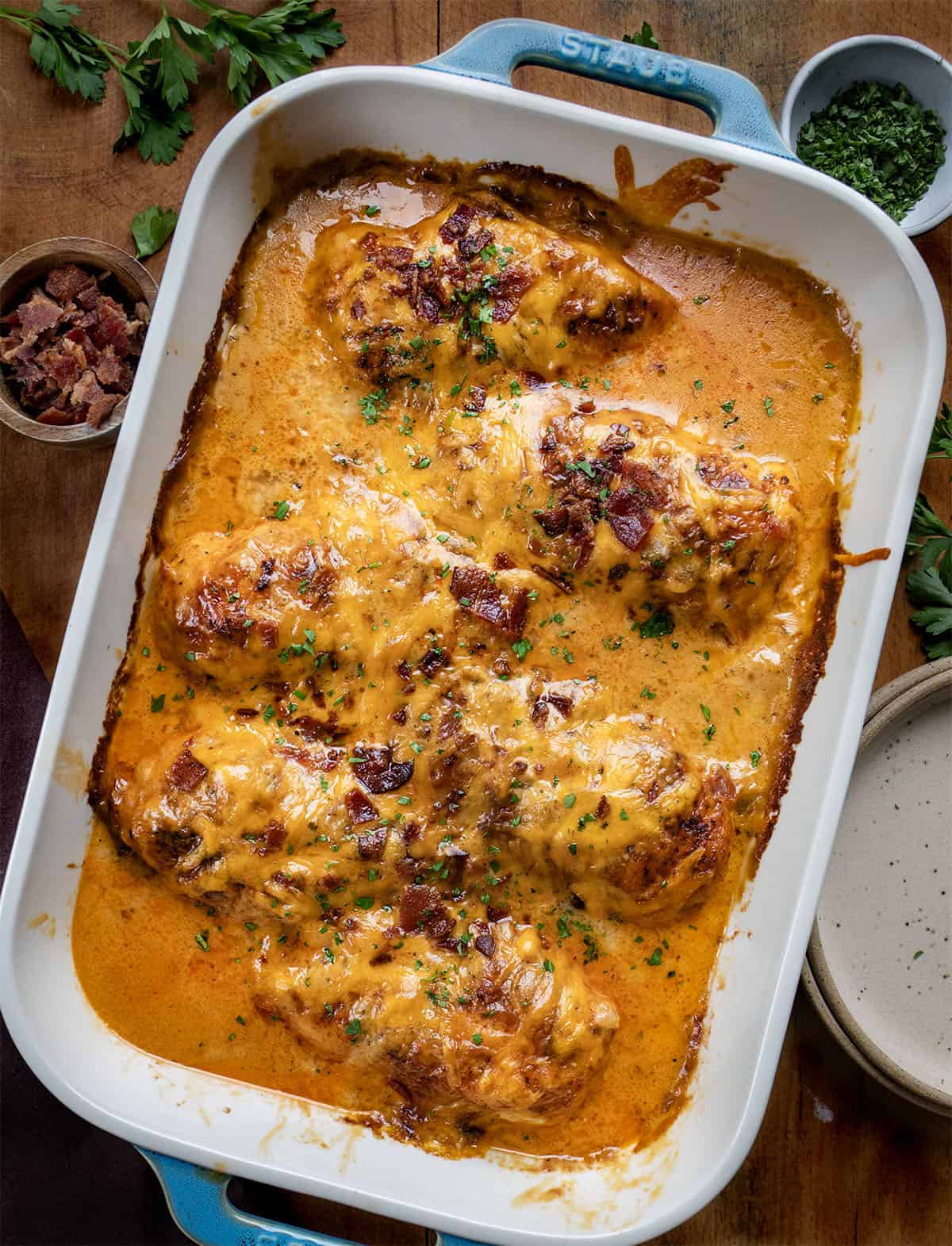 This Cheesy Ranch Chicken Casserole is a cozy baked dinner loaded with tender chicken, a creamy ranch cheese sauce, crispy bacon, and plenty of melted cheddar. It’s rich, comforting, and easy to throw together! Pan of Cheesy Ranch Chicken Casserole on a wooden table from overhead.