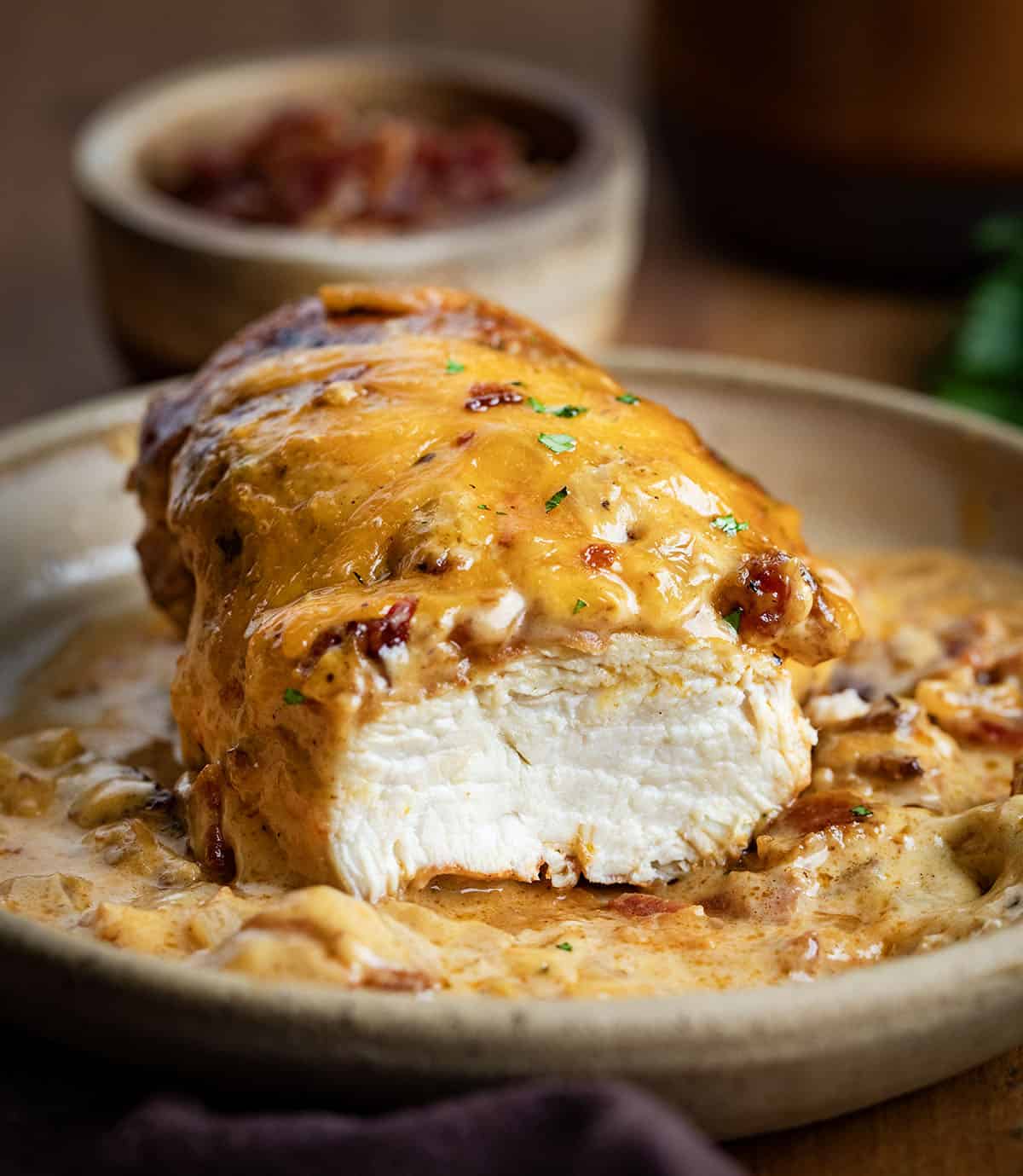 This Cheesy Ranch Chicken Casserole is a cozy baked dinner loaded with tender chicken, a creamy ranch cheese sauce, crispy bacon, and plenty of melted cheddar. It’s rich, comforting, and easy to throw together! One piece of Cheesy Ranch Chicken on a plate that has been cut, showing the inside juicy chicken.