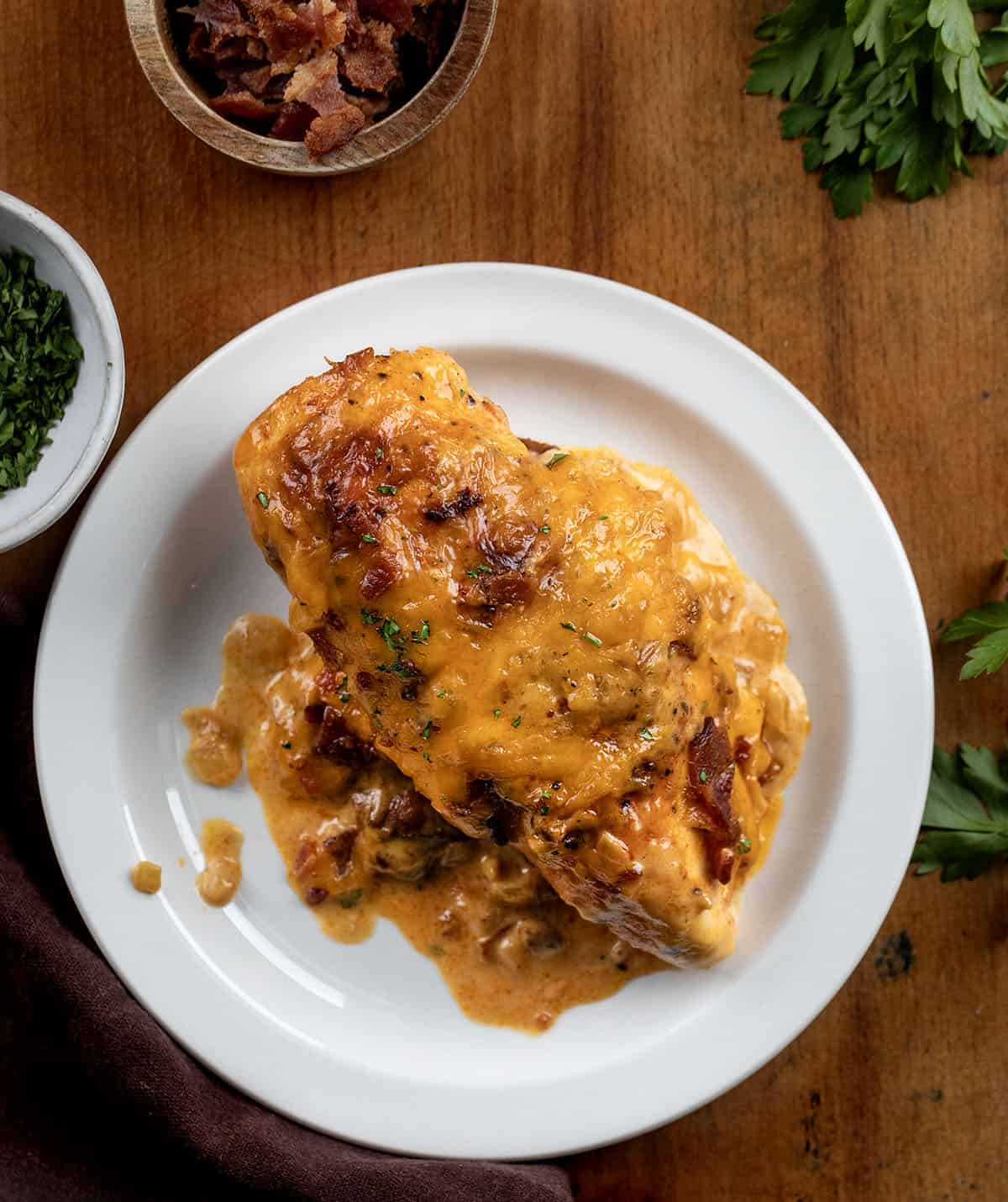 This Cheesy Ranch Chicken Casserole is a cozy baked dinner loaded with tender chicken, a creamy ranch cheese sauce, crispy bacon, and plenty of melted cheddar. It’s rich, comforting, and easy to throw together! One piece of Cheesy Ranch Chicken on a plate on a wooden table.