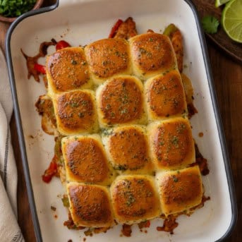 Chicken Fajita Sliders in a pan on a wooden table from overhead.