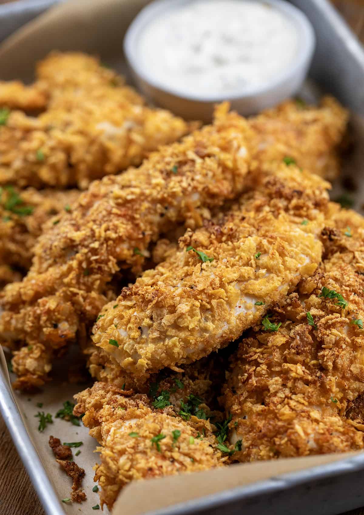 This Cornflake Chicken is crispy, golden, and baked, not fried, making it an easy weeknight dinner the whole family will love. Simple pantry ingredients come together for a no-fuss meal that’s big on flavor and short on prep time! Close up of Cornflake Chicken in a pan.