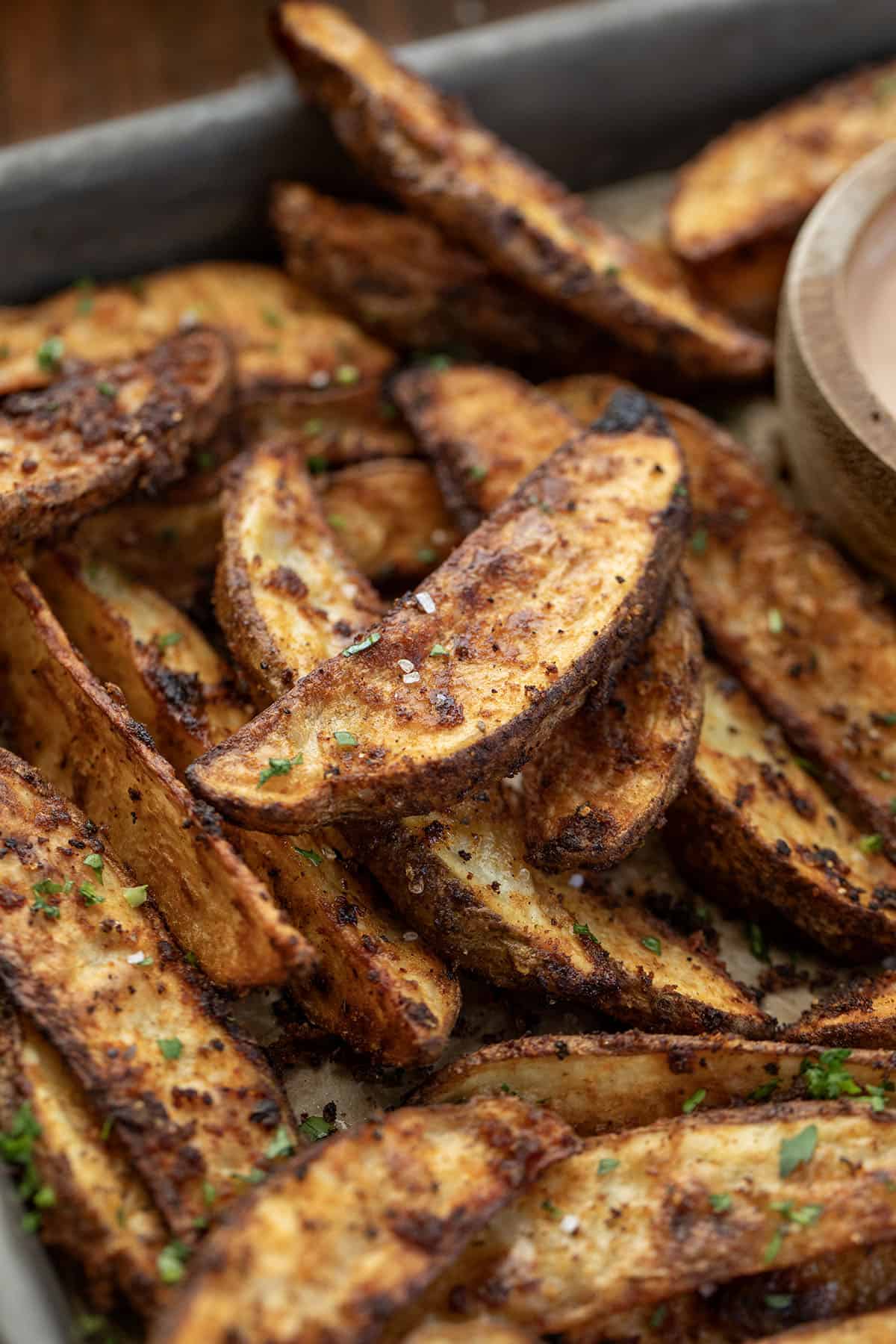 Crispy Potato Wedges on a sheet pan with dipping sauce.
