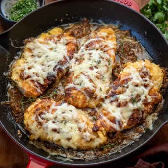 Skillet of French Onion Breaded Chicken on a wooden table from overhead.