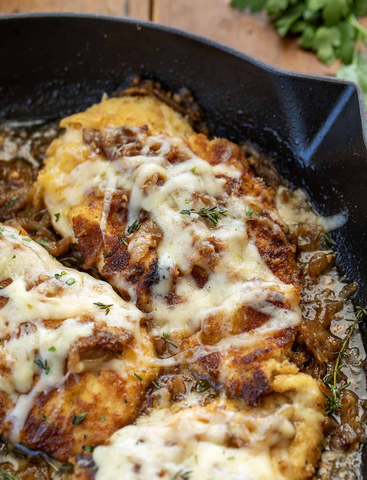 This French Onion Breaded Chicken is a cozy skillet dinner made with crispy breaded chicken, sweet caramelized onions, and melted Gruyère cheese. It’s rich, savory, and full of classic French onion flavor! Close up of a piece of French Onion Breaded Chicken.