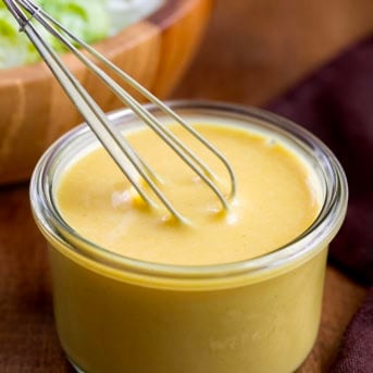 Whisking together Honey Mustard Dressing in a small glass jar.