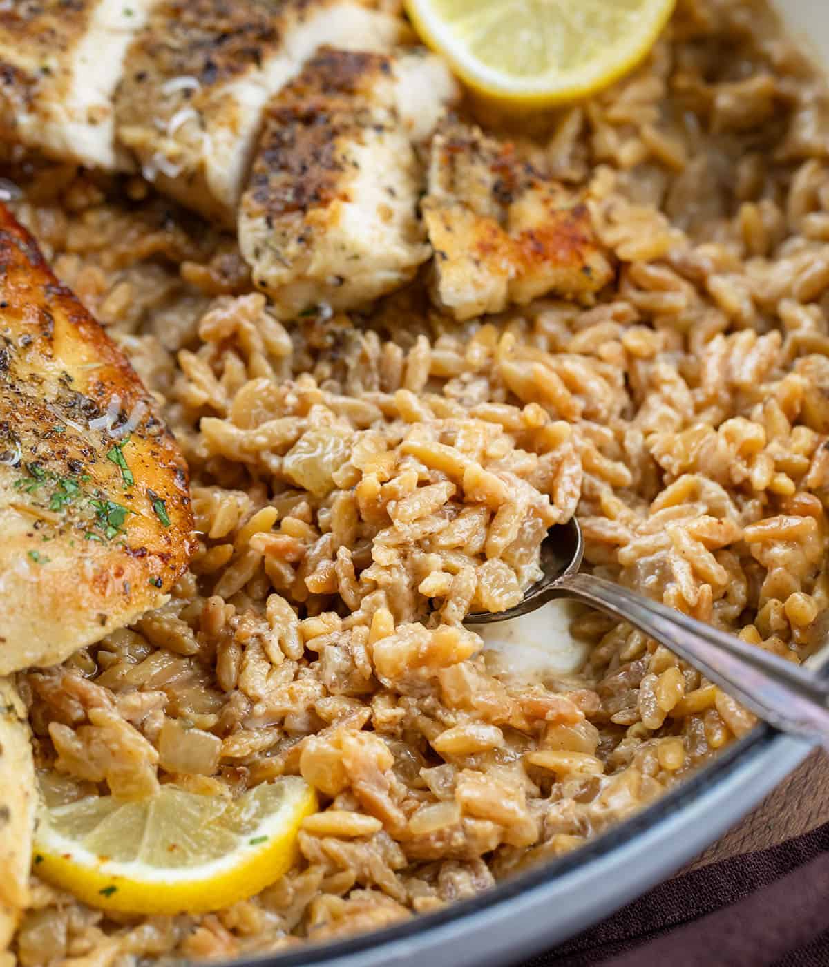 Close up of Lemon Chicken Orzo with a spoon in the pan Close up of Lemon Chicken Orzo with a spoon in the pan.