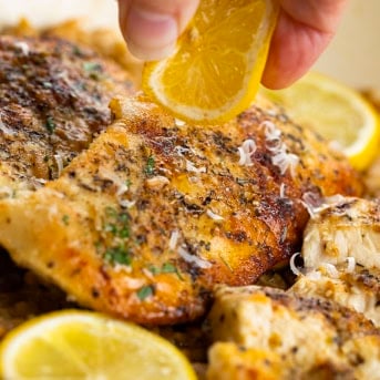 Squeezing lemon over chicken resting on orzo.