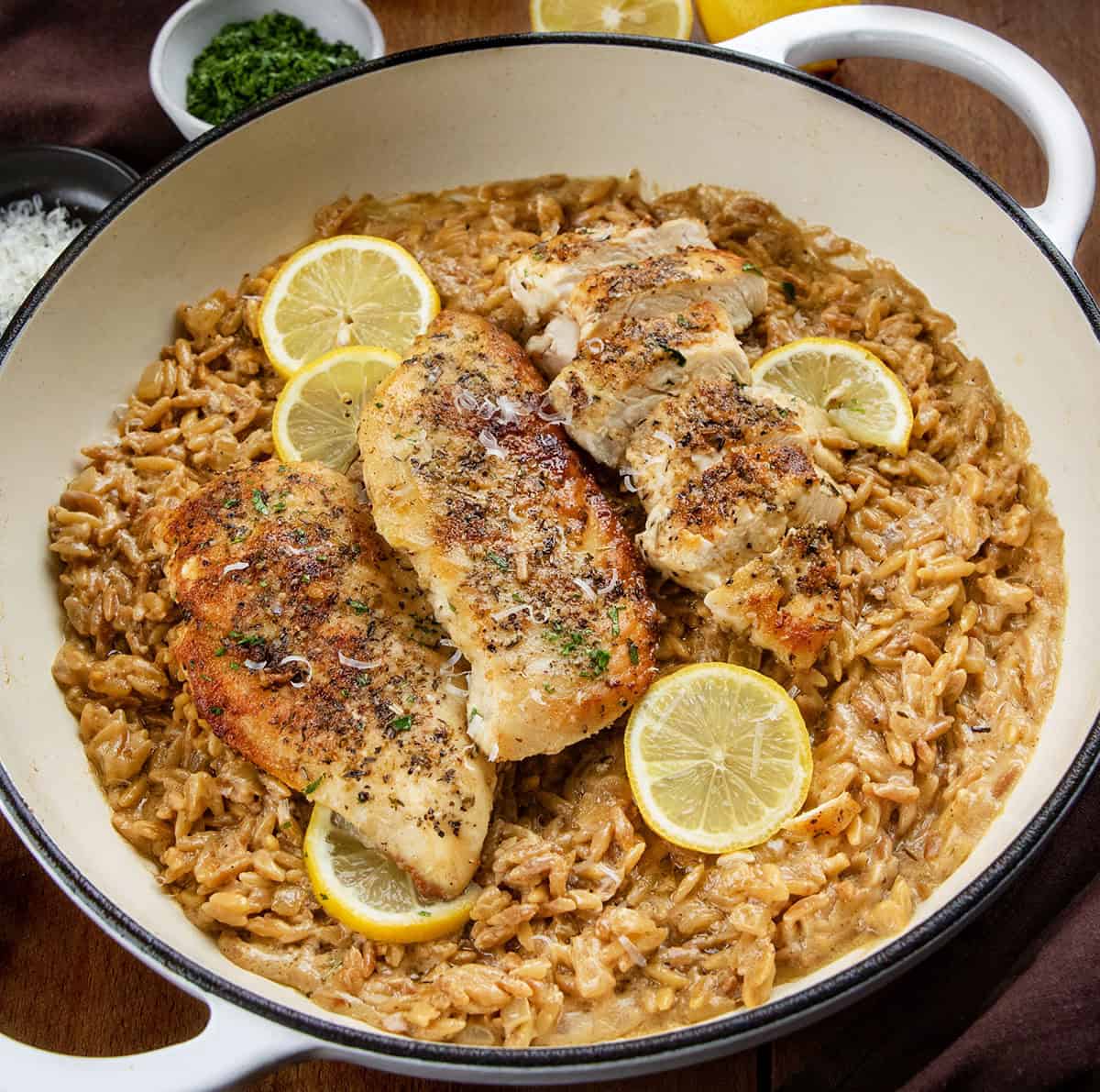 White Skillet of Lemon Chicken Orzo on a wooden table White Skillet of Lemon Chicken Orzo on a wooden table.